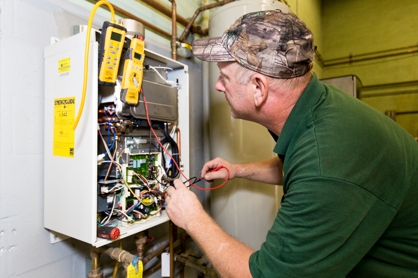 A plumber works on a gas heater system installed on the wall